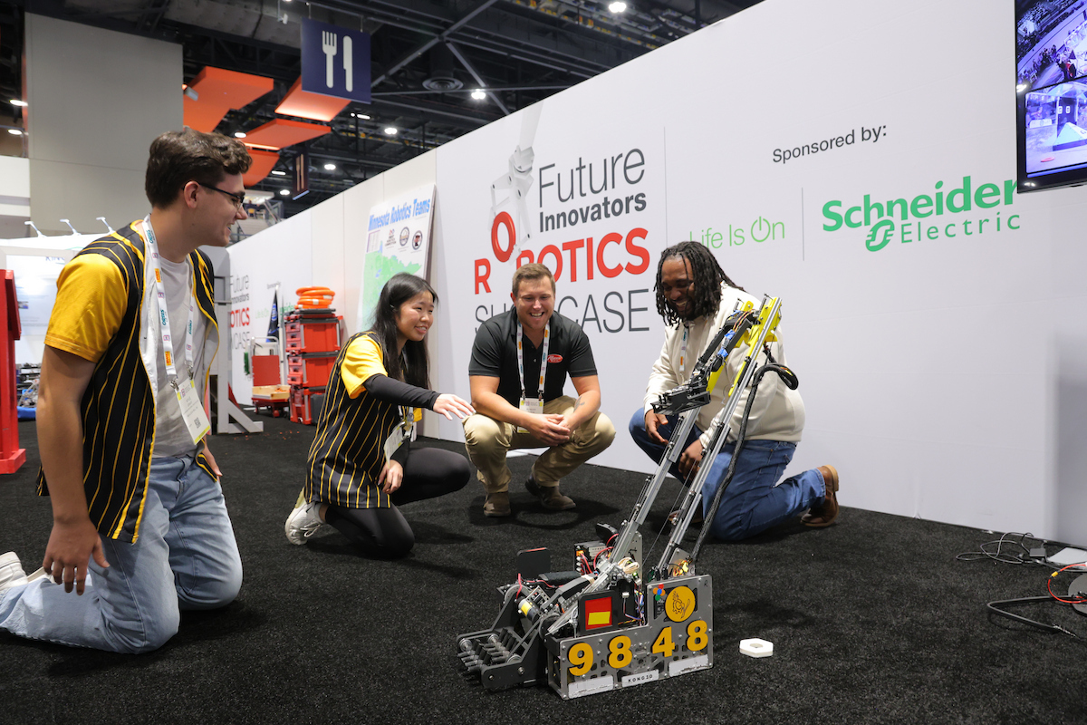 Team members demonstrate a yellow and black robot at the Future Innovators Robotics Showcase, sponsored by Schneider Electric.