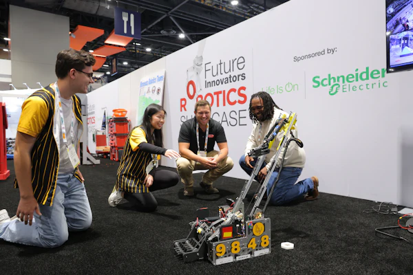 Team members demonstrate a yellow and black robot at the Future Innovators Robotics Showcase, sponsored by Schneider Electric.