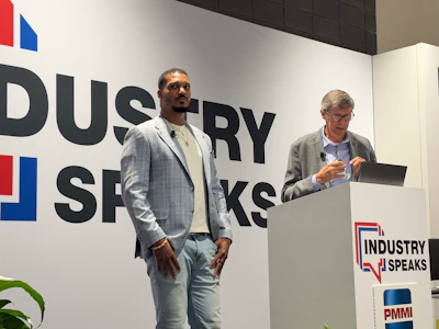 Two men presenting at Industry Speaks conference podium with PMMI branding