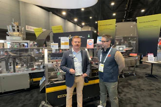 Two professionals at industrial equipment trade show booth with yellow and black ECCO machinery