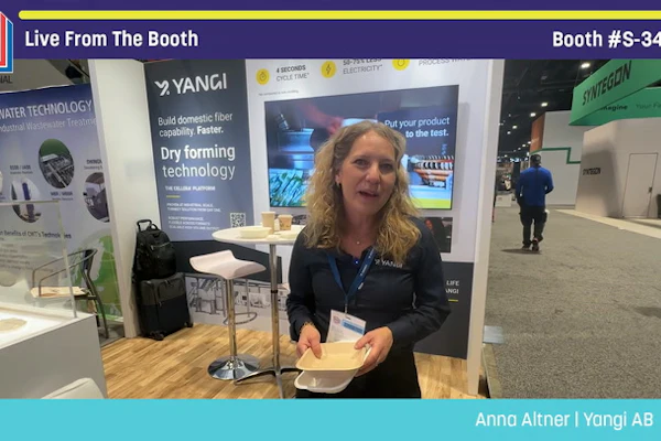 Woman presenting at Yangi AB booth during Pack Expo trade show, demonstrating dry forming technology