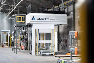 Scott Technology's Nexpal industrial hydraulic press machine in factory warehouse with yellow safety railings and equipment