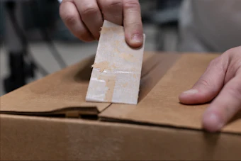 Person sealing a cardboard box with clear tape during packaging